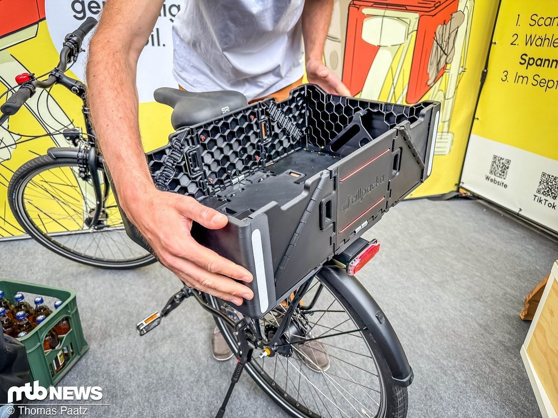 Das Aus- und Einklappen geht jetzt mit einem Handgriff in einer Sekunde vonstatten. Außerdem lassen sich gängige Fahrradtaschen an der zusammengeklappten Box befestigen. Schlau!