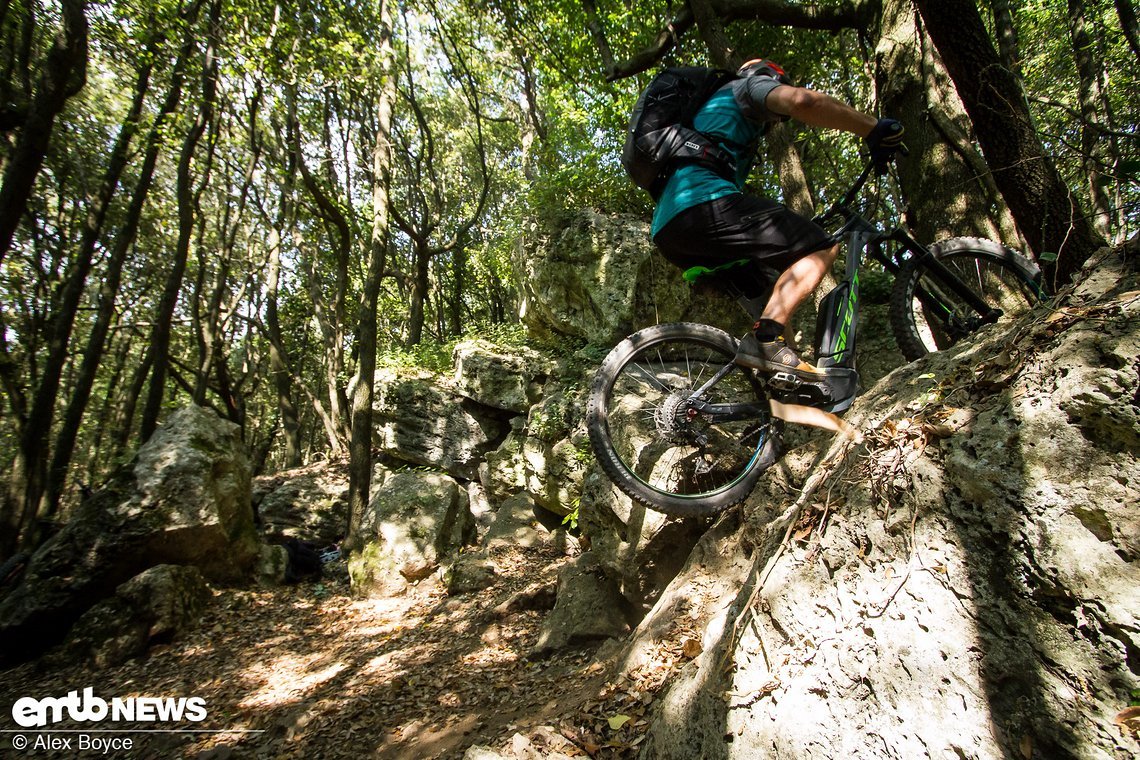 The bike keeps moving forward, Mario looks for grip and jumps upwards more draggin the bike with him, notice the rear tyre has low pressure so grips the rock hard.