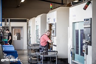 Ein Blick in die Maschinenhalle mit BROTHER Fräszentren. Horst Böttcher bestückt eine CNC Maschine mit Rohteilen. Durch das neu geschaffene Werk am Standort Mehle kann eine Aushilfe parallel mehrere Maschinen bestücken und überwachen.