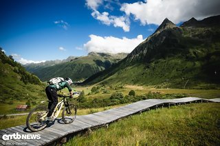 Der Trail über eine Wiese mit Moor verläuft über einen langen Holzsteg.
