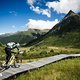 Der Trail über eine Wiese mit Moor verläuft über einen langen Holzsteg.